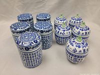 Five blue and white Chinese porcelain jar canisters with lids arranged on a surface, decorated with Chinese text and symbolic patterns.