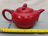 Side view of red cinnabar lacquer teapot with measuring tape showing length about 6 inches