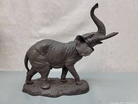 Side view of the gray cast metal elephant figurine showing detailed skin texture and raised trunk.