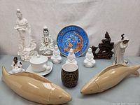 Photo showing entire collection including ceramic fish bookends, porcelain figures, decorative plate, lidded container, and wooden dragon sculpture.