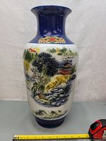 Full view of the porcelain vase showing the landscape scene and cobalt blue painted neck and base.