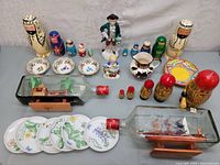Overall display of all items including nested dolls, ship in bottles, decorative plates and bowls.