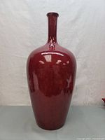 Front view of the tall dark red vase showing the rounded body and high neck.
