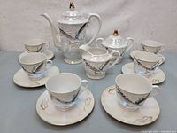 Overall view of the full tea set arranged showing cups, saucers, teapot, creamer, sugar bowl, and second taller pot
