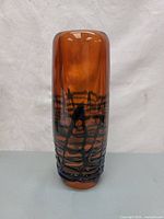 Front view of the amber glass vase with black spider web pattern.