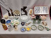 Full view of all items on table showing a variety of figurines, plates, bowls, and teapots with colorful designs.