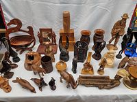 Full table view of assorted wooden figurines, animal sculptures, carved containers, and decorative pieces.