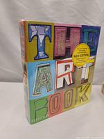 Front cover of The Art Book: New Edition by Phaidon Press with colorful block-letter title and yellow sticker advertising it as an award-winning introduction to art with new revisions and additional works.