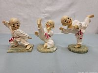 Photo of the three small resin Shaolin monk figurines in martial arts poses arranged in a row