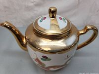 Side angle of the teapot showing gilded spout and detailed dragon painting.