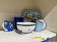 Photo showing entire set of blue decorative items including ceramic plate with bird motif, blue glass, cups and bowl.