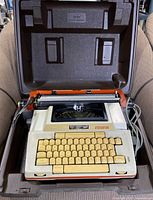 Smith-Corona Coronamatic 1200 electric typewriter inside its molded carrying case, showing keyboard and body with retro cream and orange colors.