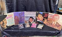 Five Frank Sinatra vinyl albums and four VHS movies laid out on a black surface.