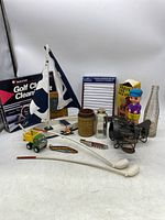 Full view of the men’s discovery lot including toys, golf accessories, sailing model, and collectibles