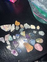 View of all 20 stones spread out on a surface, showing the variety of colors and shapes including rough and polished stones.