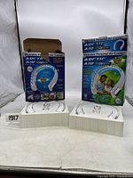 Two new Arctic Air Freedom Ultra personal air coolers displayed outside of boxes, showing front of devices with cooling vents and flexible neckbands