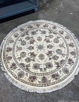 Top-down view of the round cream-colored area rug showing overall floral pattern and fringed edges.
