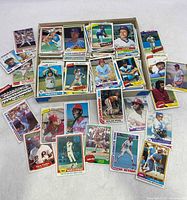 Photo showing a box with numerous vintage baseball cards including Steve Carlton, Mike Schmidt, Pete Rose and others spread around.