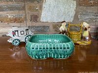 Front view of green speckled planter with stagecoach and figurine planters in background