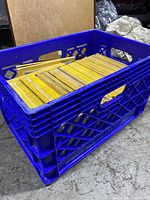 Blue plastic crate filled with vintage National Geographic magazines stacked vertically and horizontally, showing yellow bordered spines.