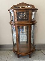 Full front view of cabinet showing curved glass doors, wood frame, and mirrored back
