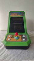 Front view of Frogger handheld arcade electronic game showing screen, joystick, and control buttons on green top panel.