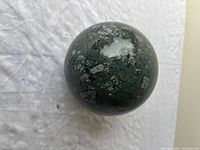 Top-down perspective of the green jasper sphere showing speckled surface detail and polished finish.