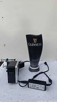 Full view of Guinness black illuminated bar display with AC power adapter and cord visible.