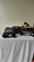 Five CB radios and scanner devices arranged on white surface, showing microphones and cables connected.