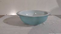 Side angle view showing turquoise blue exterior and white interior of glass mixing bowl.