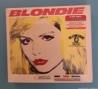 Front view of Blondie 2-CD Greatest Hits Deluxe Redux sealed in shrink wrap with yellow pop art cover featuring Debbie Harry