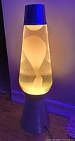 Lava lamp illuminated, showing large wax globule shapes inside clear glass with amber liquid