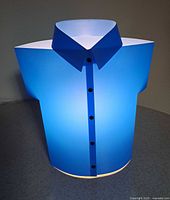 Blue plastic desk lamp shaped like a short-sleeve shirt with collar and button details, emitting light.