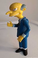 Mr. Burns figure from Simpsons wearing a blue suit, 4 inches tall, with detailed facial features and black shoes.