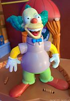 Close-up of Krusty the Clown figure with purple shirt and green pants, showing detailed facial features.