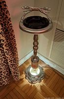 Full standing floor ashtray with illuminated base showing metal column, greyhound handle, and brown glass ashtray bowl on top