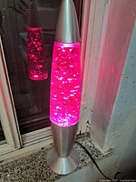 Purple fluid lava lamp with silver sparkles illuminated, showing metallic silver base and cap.