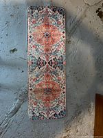 Full view of the long, narrow carpet runner displaying its complete patterned design on a concrete floor.