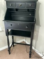 Front view of the black distressed wood desk hutch showing upper drawers, desk surface, larger drawer, and lower shelf