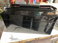 Closed black metal toolbox with cushioned handle.