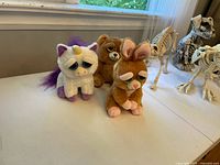 Photo showing the three plush animals (brown bear, white unicorn, brown bunny) alongside parts of the animal skeletons on a table near a window.