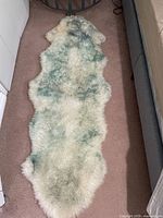 Full view of the off white sheepskin rug laid out on carpeted floor showing shape and color pattern