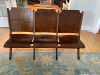 Front view of three wooden theatre seats joined together as a bench.