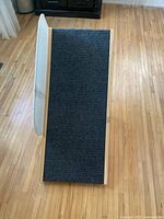 Top view of the wooden pet ramp showing the non-slip dark carpet surface and wooden frame edges.