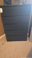 Front view of the black six-drawer IKEA dresser with all drawers closed.