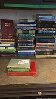 Stack of assorted religious and general books including a Holy Bible and Daily Reflections.
