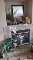 Full display against a granite fireplace with candle holders, candles, artificial plants, and metal planter stands visible