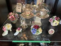 Display of all bone china floral items including two Foley teacups, various floral figurines, and plates