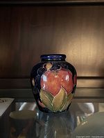 Front view of the small Moorcroft vase showing fruit and leaf hand-painted design on dark blue background.