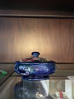 Side view of the Moorcroft lidded bowl showing the floral decoration and blue glaze.